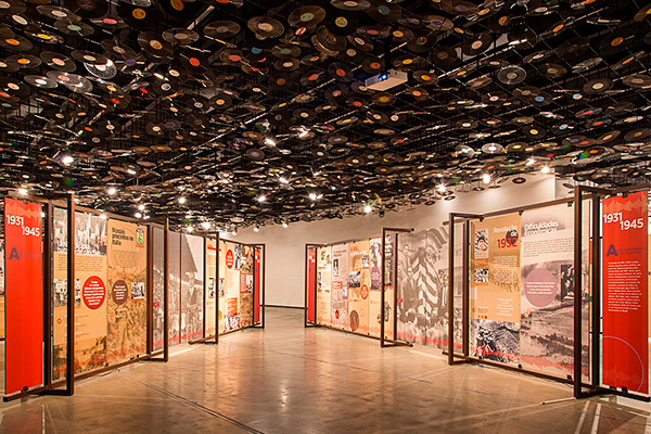 exhibition room with scenography panels and ceiling lined with old vinyl records.